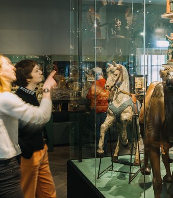 Ausstellungsansicht Weihnachten im Jägerhof zwei Frauen in einem Raum mit Vitrinen, in denen Volkskunst zu sehen ist