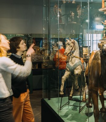Ausstellungsansicht Weihnachten im Jägerhof zwei Frauen in einem Raum mit Vitrinen, in denen Volkskunst zu sehen ist