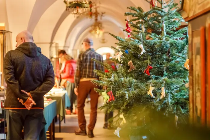 Weihnachtsbaum geschmückt mit Eislaufschuhen, im Hintergrund Besucher