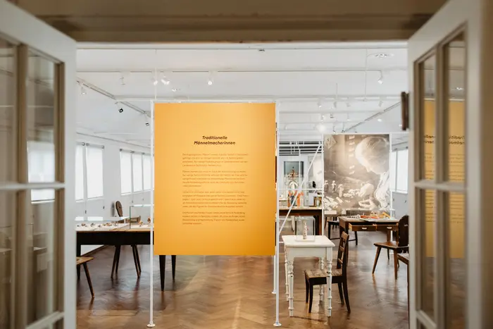 Blick in einen Ausstellungsraum mit Tischen und Infotext.