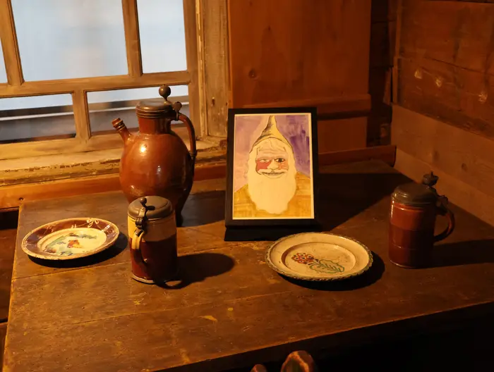 Teller, Becher und eine Zeichnung auf einem hölzernen Tisch stehend.