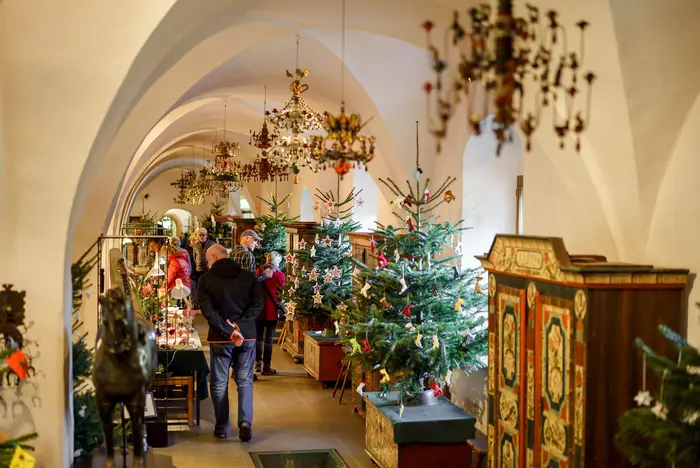 Besucher in einem Raum mit unter anderem verschieden geschmückten Weihnachtsbäumen