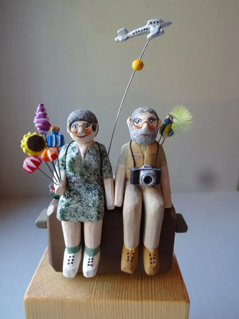 zwei Holzfiguren in Reisemontur