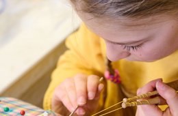 Klöppelschülerin der Volkskunstschule des Erzgebirgskreises Mädchen sitzt an einem Klöppelstück und macht eine Handarbeit