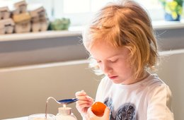 Eine ältere Frau mit Kind, das Eier an einem Tisch bemalt.