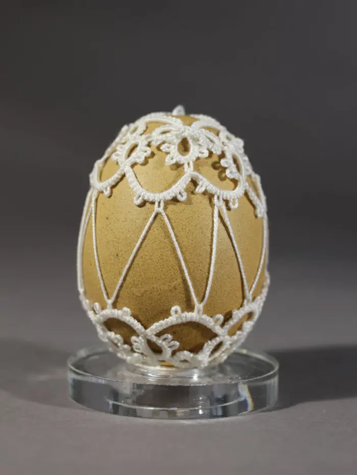 Ein Osterei, das mit Fäden kunstvoll verziert ist.