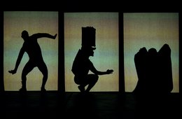 Schattentriptychon von Thulani Chauke (Entwicklung für die Jahresausstellung der Puppentheatersammlung) Schattenfiguren vor einem grünlichen Hintergrund