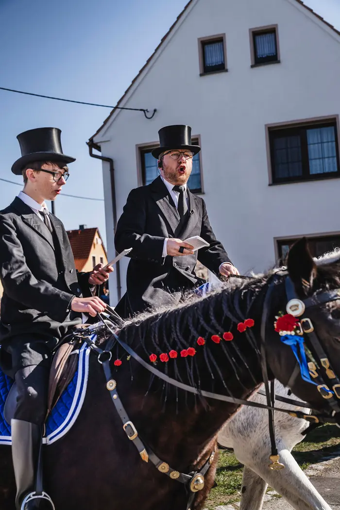 Zwei Männer mit Zylinder, die auf Pferden reiten.