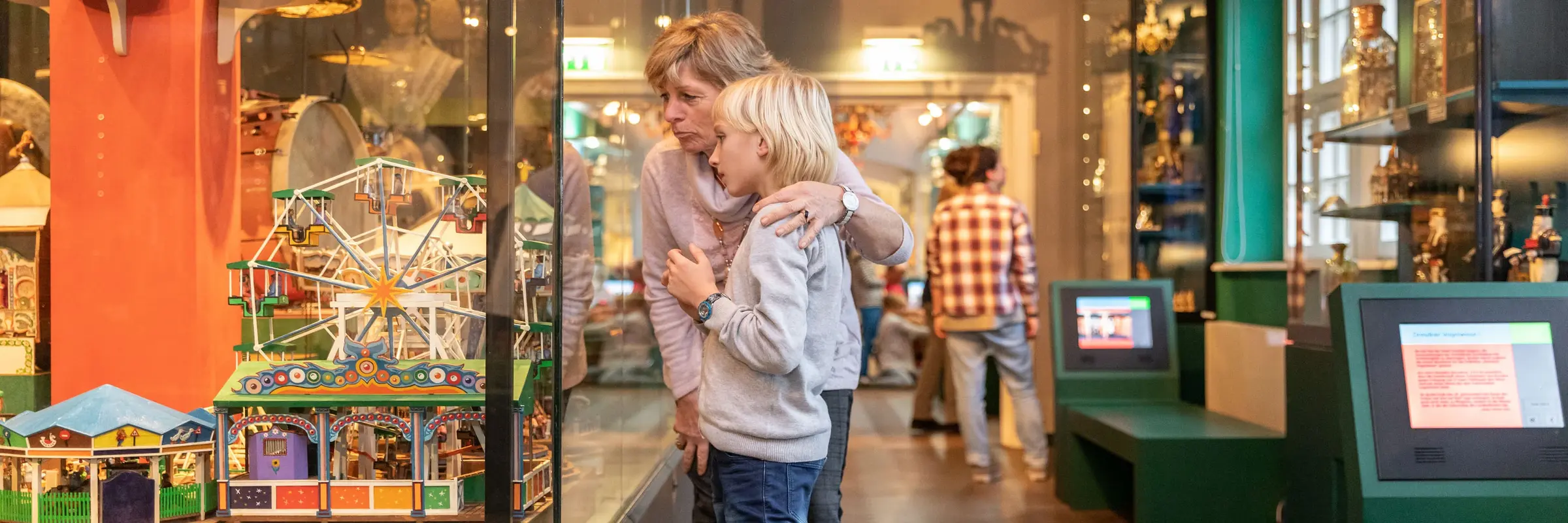 Frau mit Kind in einer Ausstellung, Objekte in einer Vitrine betrachtend.