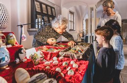 Ostern im Jägerhof eine Frau zeigt zwei Kindern und einer weiteren Person bemalte Ostereier