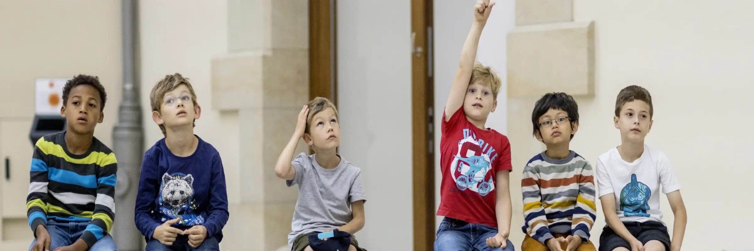 Kinder sitzen auf einer Bank im Museum
