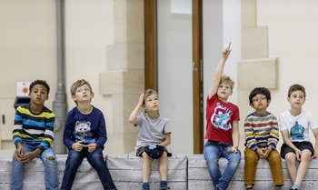 Kinder sitzen auf einer Bank im Museum