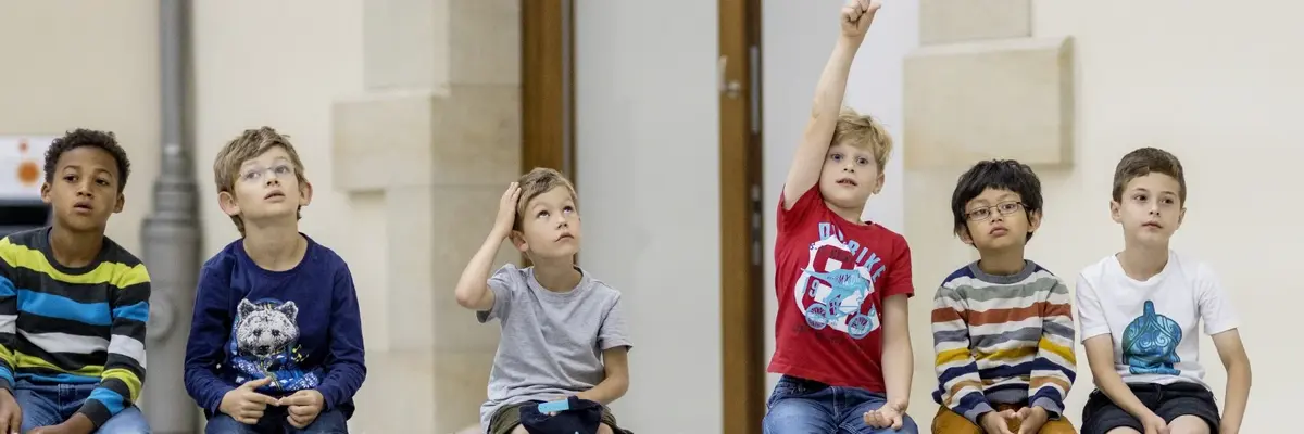 Kinder sitzen auf einer Bank im Museum