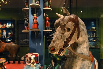 ein Karussell-Pferd, im Hintergrund kleine Figuren
