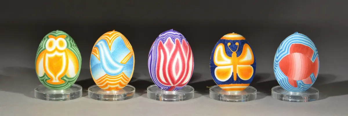 Fünf bunt bemalte Ostereier vor einem dunklen Hintergrund.