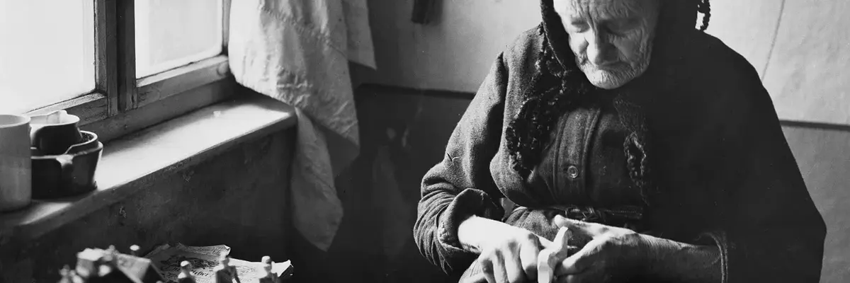 Alte Frau sitzt am Tisch und schnitzt