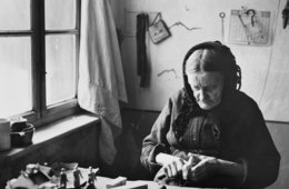 Auguste Müller beim Schnitzen Alte Frau sitzt am Tisch und schnitzt