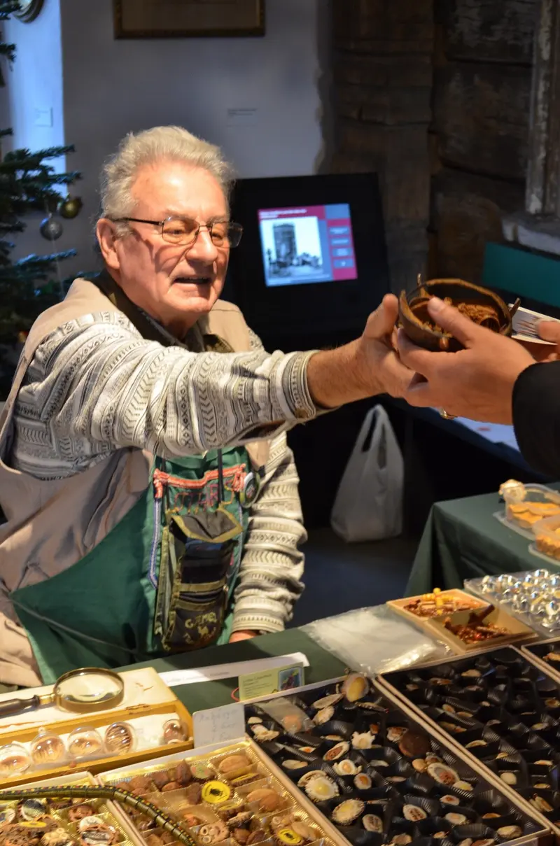 Ein älterer Mann, der seine Werke an einem Stand verkauft.