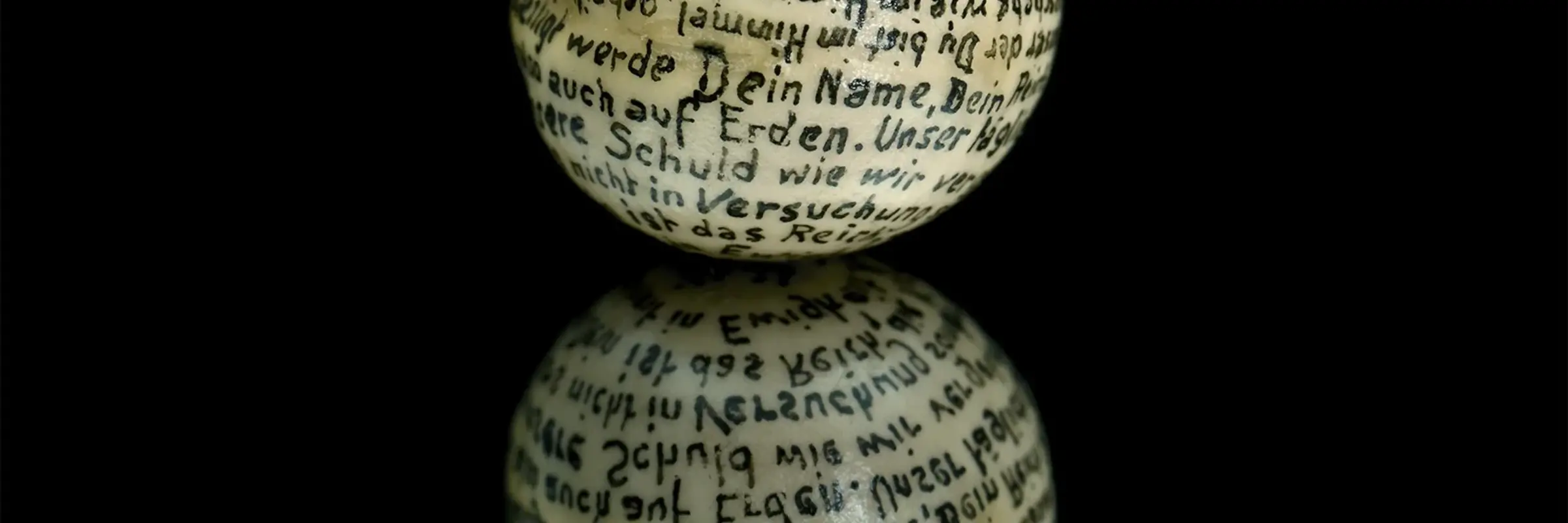 weiße Kugel mit Schrift auf schwarzem Untergrund