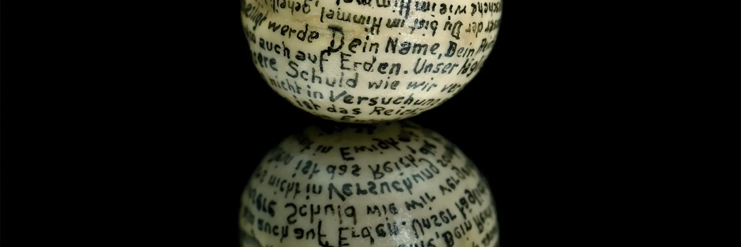 weiße Kugel mit Schrift auf schwarzem Untergrund
