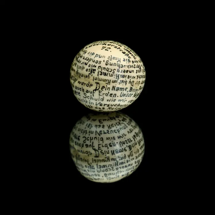 weiße Kugel mit Schrift auf schwarzem Untergrund